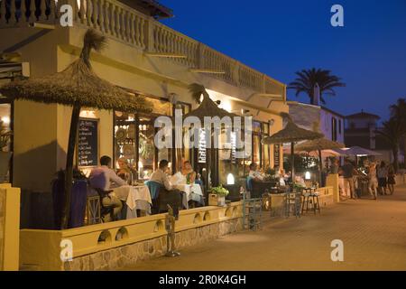Le persone si siedono all'aperto e si gustano la cena al ristorante SA Xarxa sul lungomare al crepuscolo, Colonia de Sant Pere, Maiorca, Isole Baleari, Spagna Foto Stock