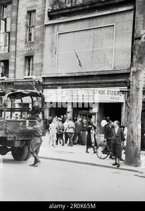 Militärlastkraftwagen und Passanten vor einem Theater, in dem die Revue 'Klingende Sterne' aufgeführt wird, im Berlin der Nachkriegszeit, Deutschland 1947. Foto Stock