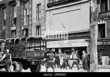 Militärlastkraftwagen und Passanten vor einem Theater, in dem die Revue 'Klingende Sterne' aufgeführt wird, im Berlin der Nachkriegszeit, Deutschland 1947. Foto Stock