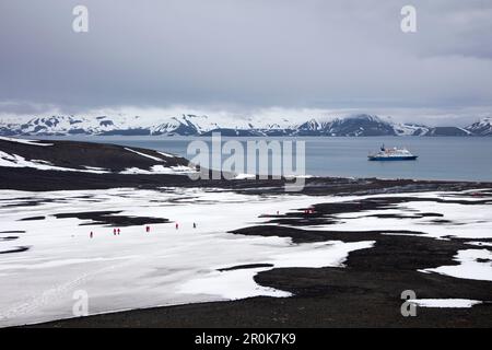 I passeggeri della nave da crociera di spedizione MV Sea Spirit (spedizioni di Poseidon) camminano attraverso il paesaggio vulcanico coperto di neve Telefon Bay, Deception Island, Foto Stock