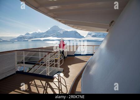 Un passeggero sul ponte della nave da crociera MV Sea Spirit (spedizione Poseidon) e montagne innevate Gerlache Strait, Graham Land, Antarcti Foto Stock