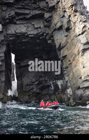 Escursione zattera Zodiac per i passeggeri della nave da crociera della spedizione MV Sea Spirit (spedizione Poseidon) lungo la parete rocciosa con apertura dell'isola di Spert, vicino a Tr Foto Stock