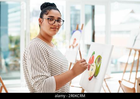 Apprezzare le cose più fini della vita. Ritratto ritagliato di un giovane artista attraente in piedi da solo e dipingere durante una classe d'arte in studio. Foto Stock