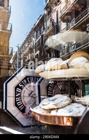 Le facciate delle vecchie case della città vecchia si riflettono nella vetrina del panettiere Horno Santo Cristo, Palma de Mallorca, Spagna Foto Stock