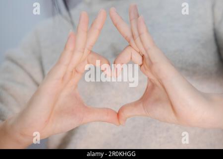 femalehand fare una forma del cuore su sfondo bianco isolato, bella mano della donna con spazio copia, il concetto di amore di san valentino Foto Stock