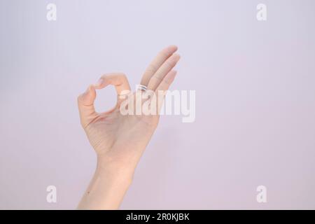 Femmina fare mano ok su bianco isolato, sfondo Closeup di donna mano gesturing - mostrando segno OK Foto Stock