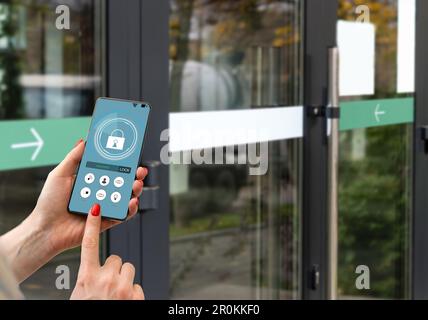 Immagine ritagliata della femmina che immette codice chiave segreto per ottenere l'accesso e passare edificio utilizzando l'applicazione sul telefono cellulare, donna premendo i pulsanti su Foto Stock