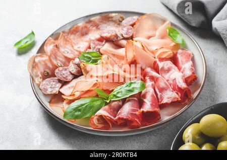 Piatto di carne stagionata, Set di antipasti, varietà di antipasti su piatto su fondo di cemento grigio Foto Stock