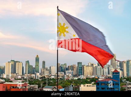 Nell'afterglow di sera presto del tramonto, la bandiera filippina rossa, blu e bianca vola, con il suo sole dorato e le stelle che mostrano, nella brezza calda, su un Foto Stock