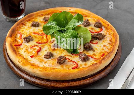 Pizza con paprika e roast beef su tagliere su tavolo di pietra Foto Stock