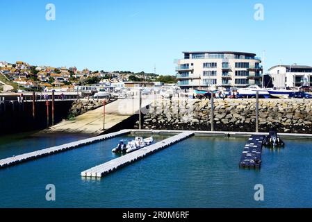 Pontoni galleggianti nel porto con edifici cittadini tra cui l'Ellisse sul retro, West Bay, Dorset, Regno Unito, Europa. Foto Stock