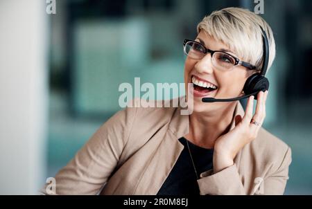 Grazie per il feedback positivo. una giovane donna d'affari che indossa una cuffia mentre lavora su un computer in ufficio. Foto Stock