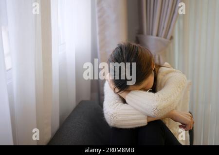 Bella donna con triste emozione sedersi sul divano. Concetto di vita e di emozione negativa. Foto Stock