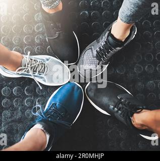 Sai che youre vincendo quando youre indossare scarpe palestra. un gruppo di persone in piedi insieme in un cerchio in palestra. Foto Stock