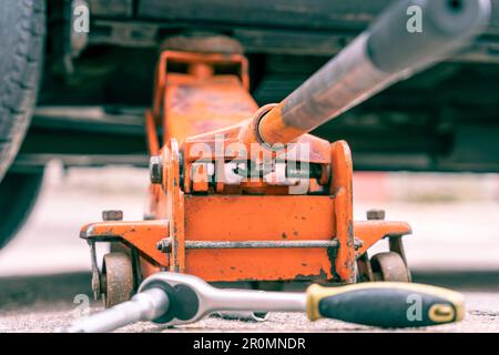 sostituzione delle ruote per auto. sollevare il veicolo con l'elp del martinetto idraulico. Foto Stock