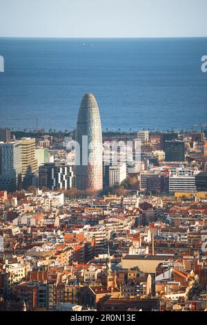 Vista aerea della moderna e alta torre Agbar situata tra edifici residenziali e grattacieli vicino al mare nella soleggiata città di Barcellona Foto Stock