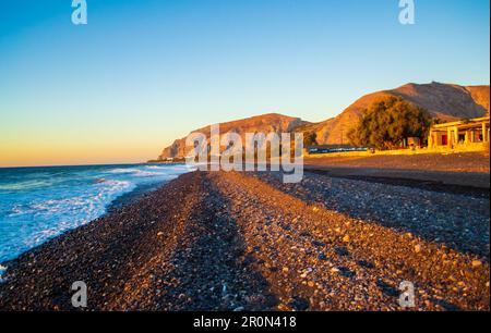 Ciottoli neri alla spiaggia di Avis e Mesa Vouno. Si trova vicino all'estremità meridionale dell'aeroporto internazionale di Santorini. Kamari Grecia,2013 Foto Stock