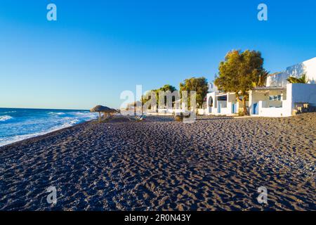 Le ville in ciottoli neri e sulla spiaggia di Avis Beach. Si trova vicino all'estremità meridionale dell'aeroporto internazionale di Santorini, Kamari, Grecia Foto Stock