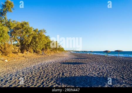 Le ville in ciottoli neri e sulla spiaggia di Avis Beach. Si trova vicino all'estremità meridionale dell'aeroporto internazionale di Santorini, Kamari, Grecia Foto Stock