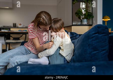 Affettuoso giovane mamma premurosa abbracciare sconvolto o addolorato figlio adolescente aiutare a sostenere. Foto Stock