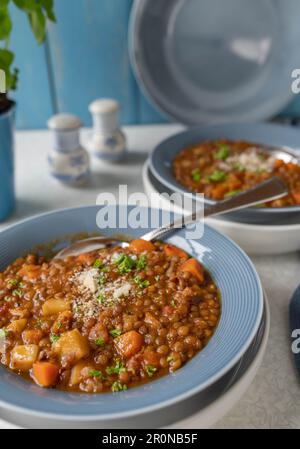 Stufato di lenticchie con pomodori, sedano, carote, erbe aromatiche e pancetta. Condito con parmigiano. Cucina italiana Foto Stock