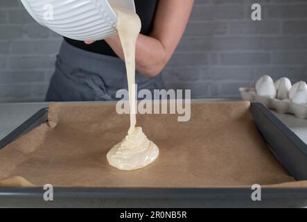 Versare l'impasto su una teglia da forno. Blocca movimento Foto Stock