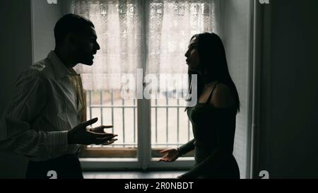 Un uomo arrabbiato che urla contro la donna. Scena drammatica di coppia urlando l'uno contro l'altro in disputa. Le persone litigano durante la crisi, puntano le dita e incolpano Foto Stock