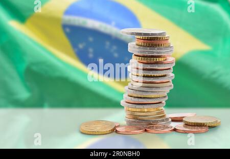 Monete impilate l'una sull'altra in diverse posizioni con bandiera brasiliana Foto Stock