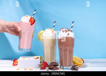 Set di frullati rinfrescanti o frullati estivi dal gusto classico e delizioso - limone alla vaniglia, fragola, cioccolato, con panna montata e condimenti, Foto Stock