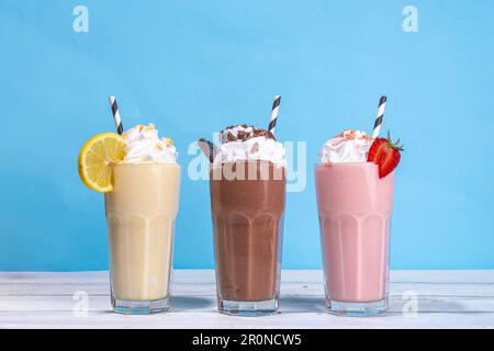 Set di frullati rinfrescanti o frullati estivi dal gusto classico e delizioso - limone alla vaniglia, fragola, cioccolato, con panna montata e condimenti, Foto Stock