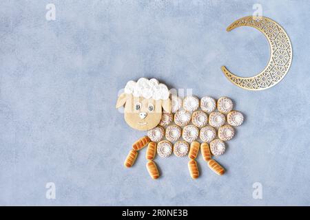 Biglietto d'auguri EID al Adha Mubarak con biscotti di semola maamoul disposti a forma di pecora. Tradizionale vacanza musulmana. EID al Adha concetto sfondo Foto Stock