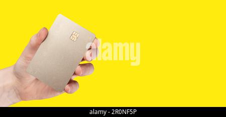 Banca carta di credito mock in mano su sfondo giallo banner. Foto Stock
