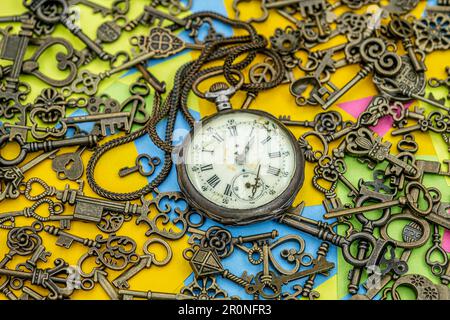 Il concetto di simbolismo. Orologio da tasca marcio antico con tasti ornamentali in bronzo su uno sfondo di carta policroma note appiccicose Foto Stock