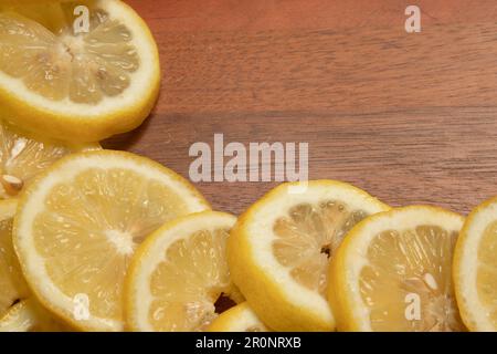 fette di limone giallo su tagliere di legno, taglio fresco, utilizzate per creare piatti saporiti, limonata, dessert al limone, acqua di limone Foto Stock