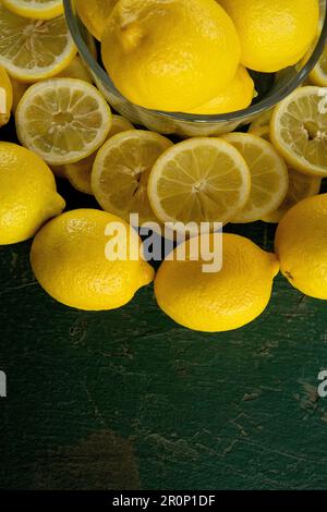 limoni interi e a fette disposti in un disegno circolare su un tavolo verde dipinto rustico peeling vecchio Foto Stock