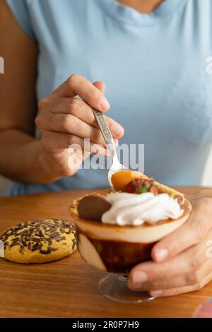 gustando con un cucchiaio un delizioso dolce decorato con vari condimenti, gelato e biscotti, carta da parati in uno studio alimentare, dolci gourmet Foto Stock
