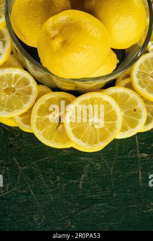 limoni interi e a fette disposti in un disegno circolare su un tavolo verde dipinto rustico peeling vecchio Foto Stock