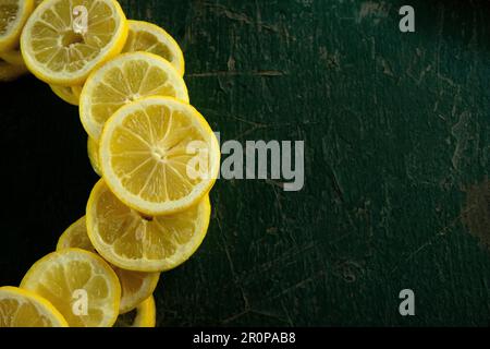 limoni interi e a fette disposti in un disegno circolare su un tavolo verde dipinto rustico peeling vecchio Foto Stock