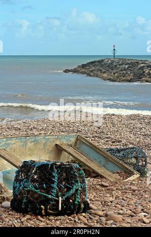 SIDMOUTH, DEVON, Regno Unito - 21 MARZO 2017 aragoste pentole e relitto barca sulla spiaggia di ciottoli Foto Stock