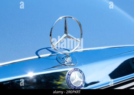 Primo piano del vecchio logo originale in metallo della Mercedes Benz sul cofano dell'auto. Fuoco selettivo del vecchio logo Mercedes. Foto Stock