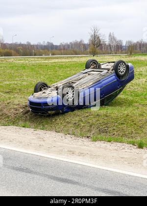 Auto incidente scena, una vettura passeggeri ha lasciato la strada e ribaltato con le ruote in alto, auto ribaltata Foto Stock