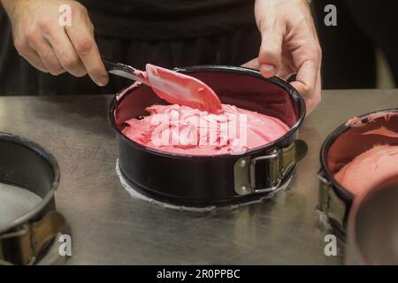 chef preparare impasti cremosi per torte rosse bianche rosa da cuocere in forno Foto Stock