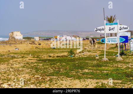 Sidi Kaouki, Marocco - 07 aprile 2023: Vista della località balneare di Sidi Kaouki, con vari segni e un cavallo. Marocco Foto Stock