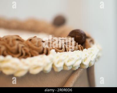 elegante torta di ghiaccio marrone beige glassato macro primo piano isolato su sfondo bianco per la celebrazione Foto Stock