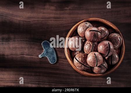 Noci di macadamia in legno chiave ciotola per aprire su legno d'epoca Foto Stock