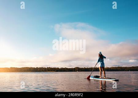 Voglio andare dove i miei piedi non possono portarmi. una giovane donna pagaia imbarco su un lago. Foto Stock