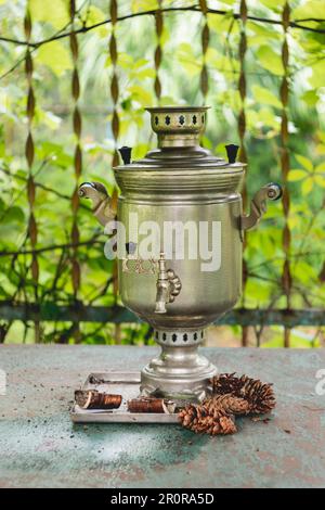 Samovar d'epoca - vecchio bollitore tradizionale russo. Apparecchio in metallo retrò per bollire l'acqua. Coni di pino e corteccia di albero possono essere usati come combustibile. Foto Stock