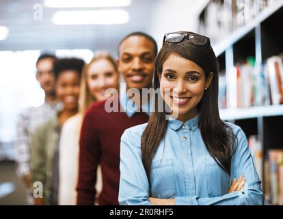 Rimanete concentrati e non arrogatevi mai. studenti universitari in piedi nella biblioteca del campus. Foto Stock