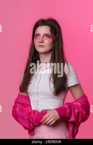 Ritratto di una donna di 22 anni con make-up rosa, vestita con giacca rosa, gonna e t-shirt bianca. Studio shot di bella ragazza hipster Foto Stock