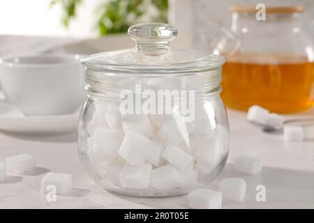 Vasetto con zucchero raffinato, miele e tisana su tavolo bianco Foto Stock